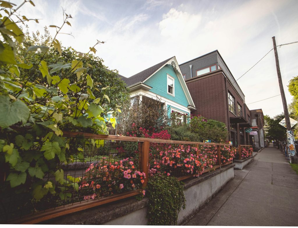 Grünes und weißes Holzhaus in der Nähe von grünen Bäumen unter weißer Wolkenbedeckung am Tag